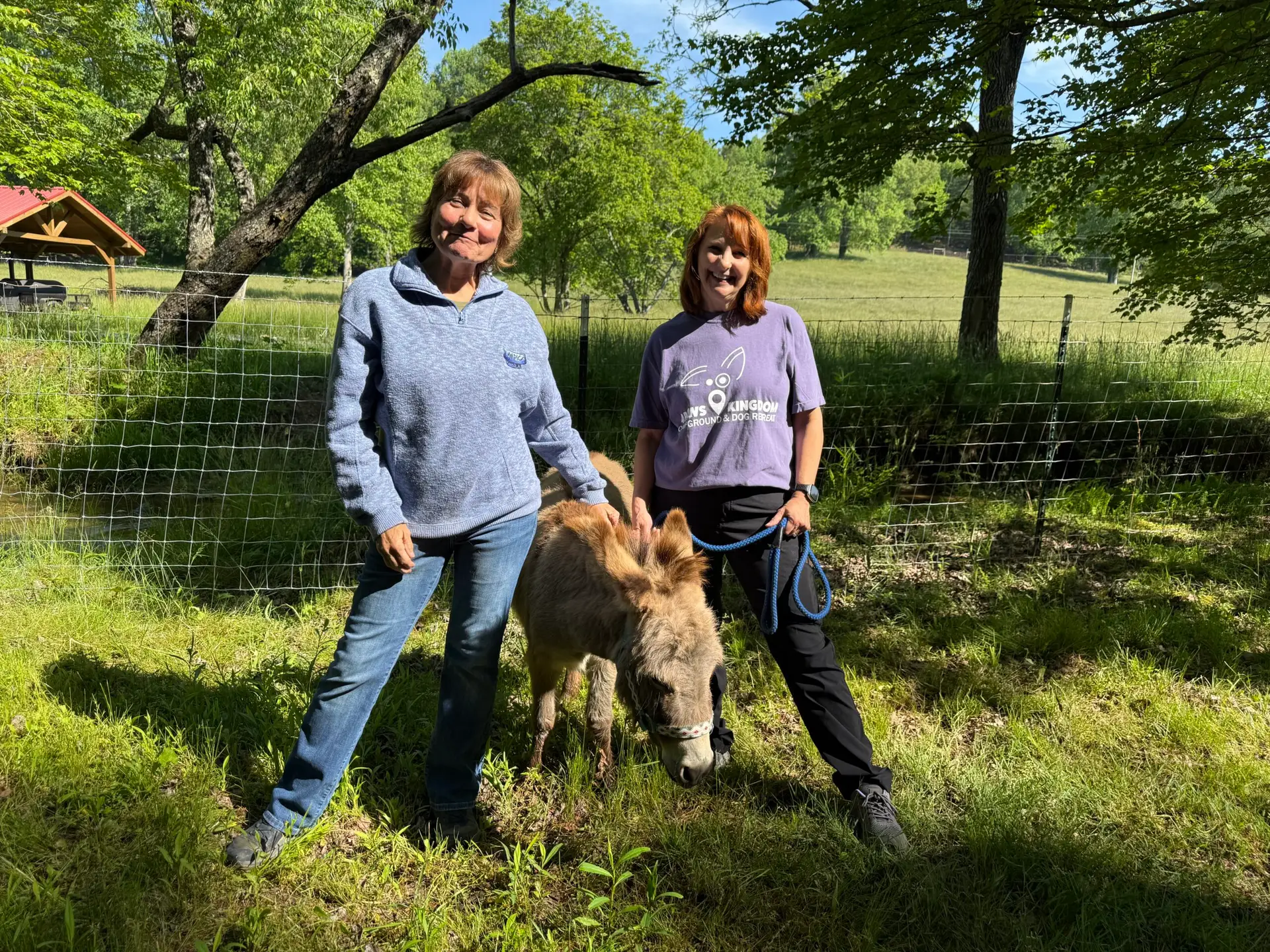 two women with a miniature donkey between them